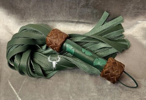 Green leather flogger with a dark green handle featuring hand-carved ginko leaf patterns and brown braided leather knots.